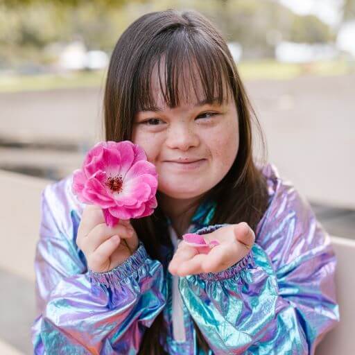 Young girl with Downs Syndrome holding a flower
