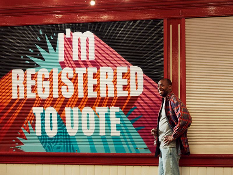 Man standing next to poster that states 'I'm registered to vote'.