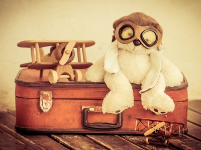 Old toys including a teddy bear, suitcase and two planes