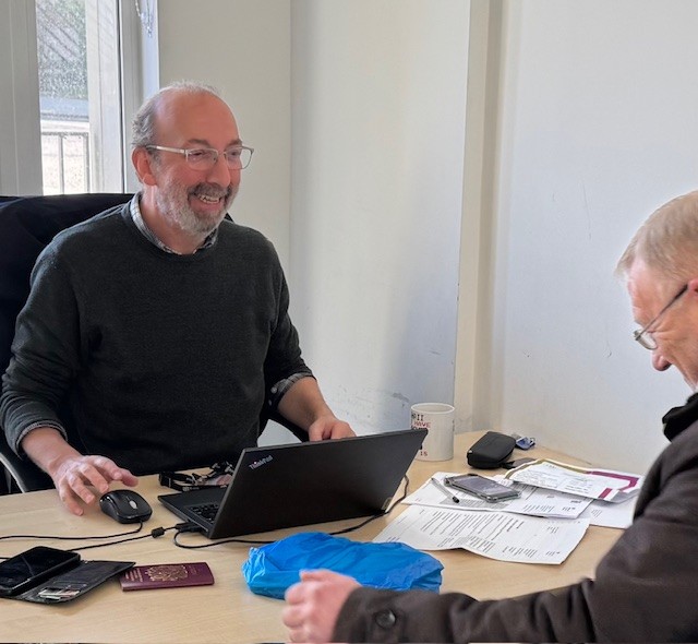 two men sitting by a desk and talking